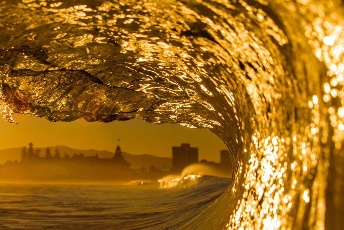 Golden-hued ocean wave with cityscape in the background